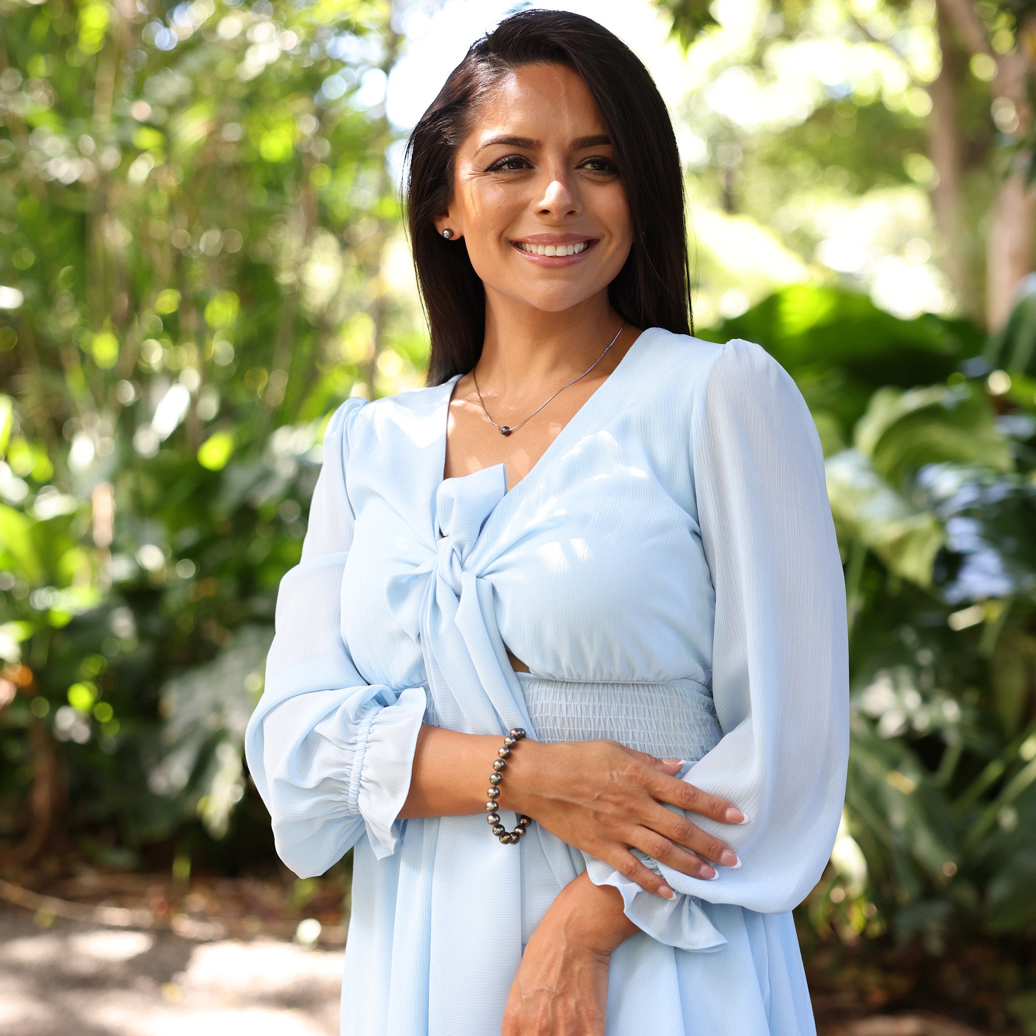 Woman in blue dress wearing 18" Tahitian Black Pearl Necklace in Sterling Silver at Hawaiian tropical garden